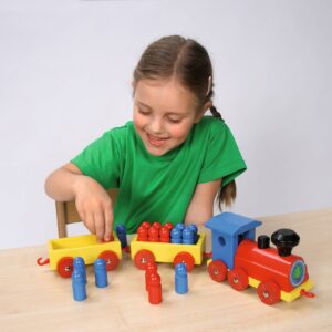 Houten reken trein met kleurrijke wagons en cijfers, een meisje plaatst houten figuren in de trein.