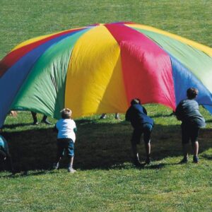 Kleurrijke mega parachute van nylon, gebruikt door kinderen voor teamactiviteiten op grasveld.