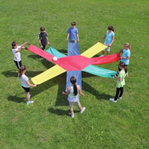 Kleurrijk parachutedoek in gebruik door kinderen, die samenwerken en een bal omhoog houden op een grasveld.