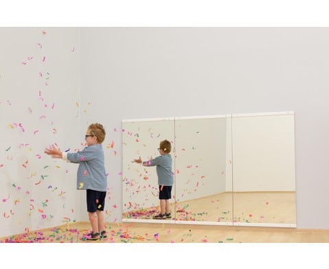 Spiegelwand Verticaal met een kind dat speelt met confetti, weerspiegeld in de verticale spiegels.
