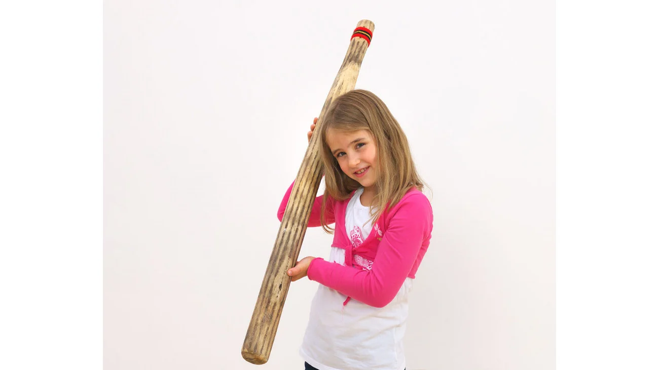 Rainmaker van 100 cm, een houten muziekinstrument, vastgehouden door een meisje met een roze shirt.