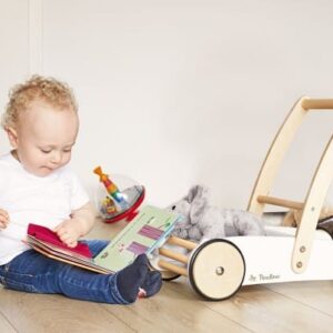 Witte opbergkist met deksel, ideaal voor speelgoed, naast een peuter die een boek leest op de vloer.