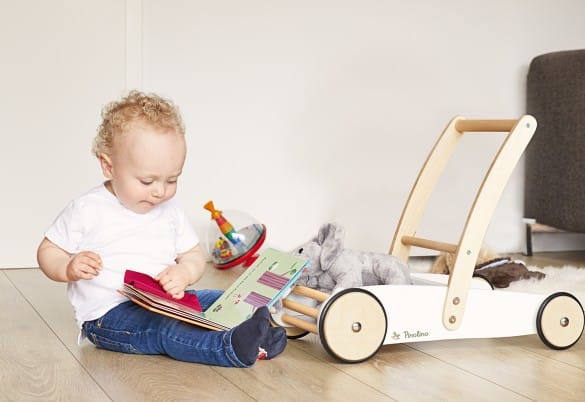 Witte opbergkist met deksel, ideaal voor speelgoed, naast een peuter die een boek leest op de vloer.