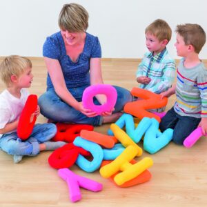Kleurrijke, zachte stoffen letters XL in verschillende kleuren, gebruikt door kinderen tijdens een taalles met een volwass...