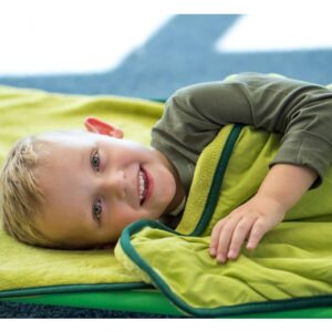 Zacht ligbed met geïntegreerde slaapzak, kind ligt comfortabel en glimlacht, ideaal voor kinderopvang en peuterruimtes.