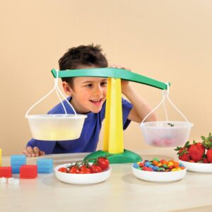 Kunststof weegschaal met transparante bakjes, kleurrijke blokken en fruit, ideaal voor leren wegen en vergelijken.