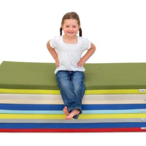Comfort Matras met zachte schuimvulling, stapelbaar, met een meisje in een witte blouse zittend op de matras.