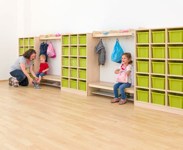 Chippo Garderobe Kast met groene opbergboxen, jassen en kinderen die spelen in een kindvriendelijke ruimte.