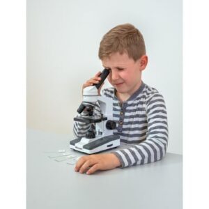 Kind met een microscoop op een tafel, kijkt door de lens, omringd door preparaten en eenvoudig te bedienen knoppen.