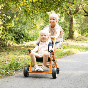 Kinderen duwen elkaar in een oranje Toffe Buggy met zwenkwielen, ideaal voor buiten spelen en het vervoeren van knuffels.