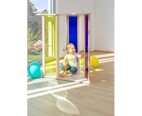 Kleurendriehoek van EduCasa met transparante panelen in geel, blauw en rood, gebruikt door een spelend kind.