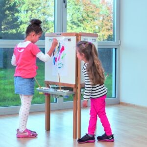 Driehoekige schildersezel voor kinderen, met twee kinderen die creatief bezig zijn met verf en papier. Hoogte 55 cm.