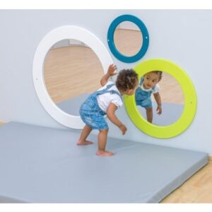 Ronde M-Lime spiegel in levendige limekleur, veilig voor kinderen, met een kind dat erin kijkt op een zachte ondergrond.