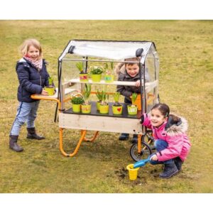 Mobiele plantenkas met wielen, gevuld met kleurrijke potten en kinderen die planten verzorgen op een grasveld.