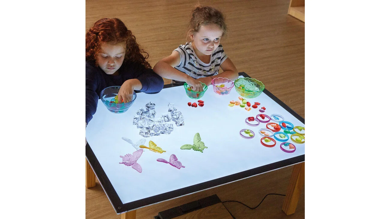 Lichttafel A1 met kinderen die kleurrijke materialen en schalen gebruiken voor spelenderwijs lichtexperimenten.