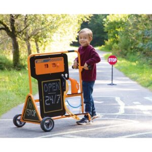 Mobiel tankstation met stopbord, jongen in rode trui, speelt op een fietspad in een groene omgeving.