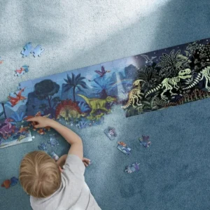 Puzzel met dinosaurussen die oplichten in het donker, kind legt stukjes op een blauwe vloer.