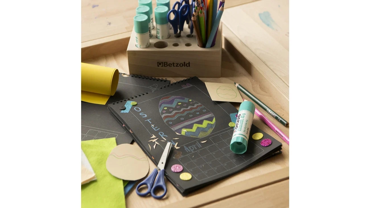 SET van 10 zwarte kalenders om zelf te ontwerpen, omringd door knutselmaterialen en kleurrijke pennen.