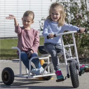 Kinder Taxi Buddy Plus met twee kinderen, één zwaaiend, op een driezitter met robuuste wielen, ideaal voor samen rijden.