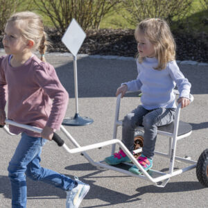 Kinderen spelen met een riksja, één als passagier en de ander trekt, ideaal voor rollenspel buiten.