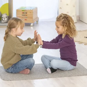 Grijs laagpolig tapijt van 60 x 100 cm, gebruikt door twee kinderen die samen spelen op een houten vloer.