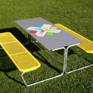 Buitenmeubilair: Zitgroep met gele banken en een speeltafel voor MENS ERGER JE NIET op een groene grasvloer.