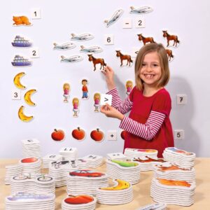 Magnetische rekenplaatjes met dieren, voertuigen en fruit, gebruikt door een kind op een bord voor rekenactiviteiten.