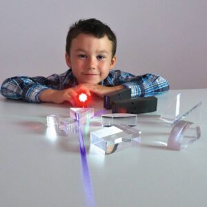 Kind met LED-kleurenlampen en transparante objecten, experimenteert met licht en kleur op een tafel.