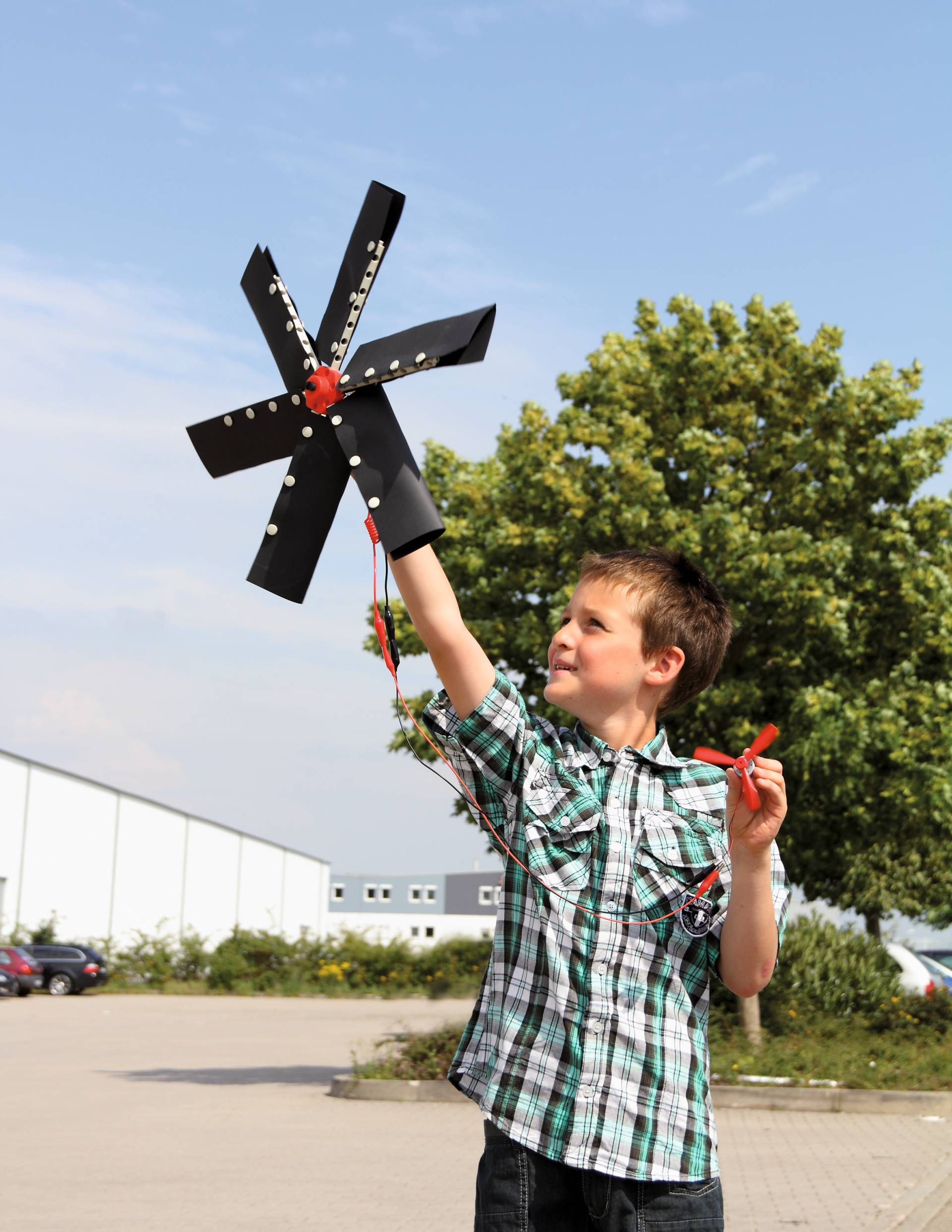 Jongen met een windmolenmodel in de hand, leert over alternatieve energiebronnen buiten.