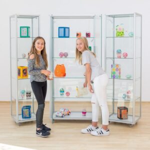 Vitrinekast met aluminium frame en gehard glas, gevuld met kleurrijke tentoonstellingsstukken en twee meisjes.