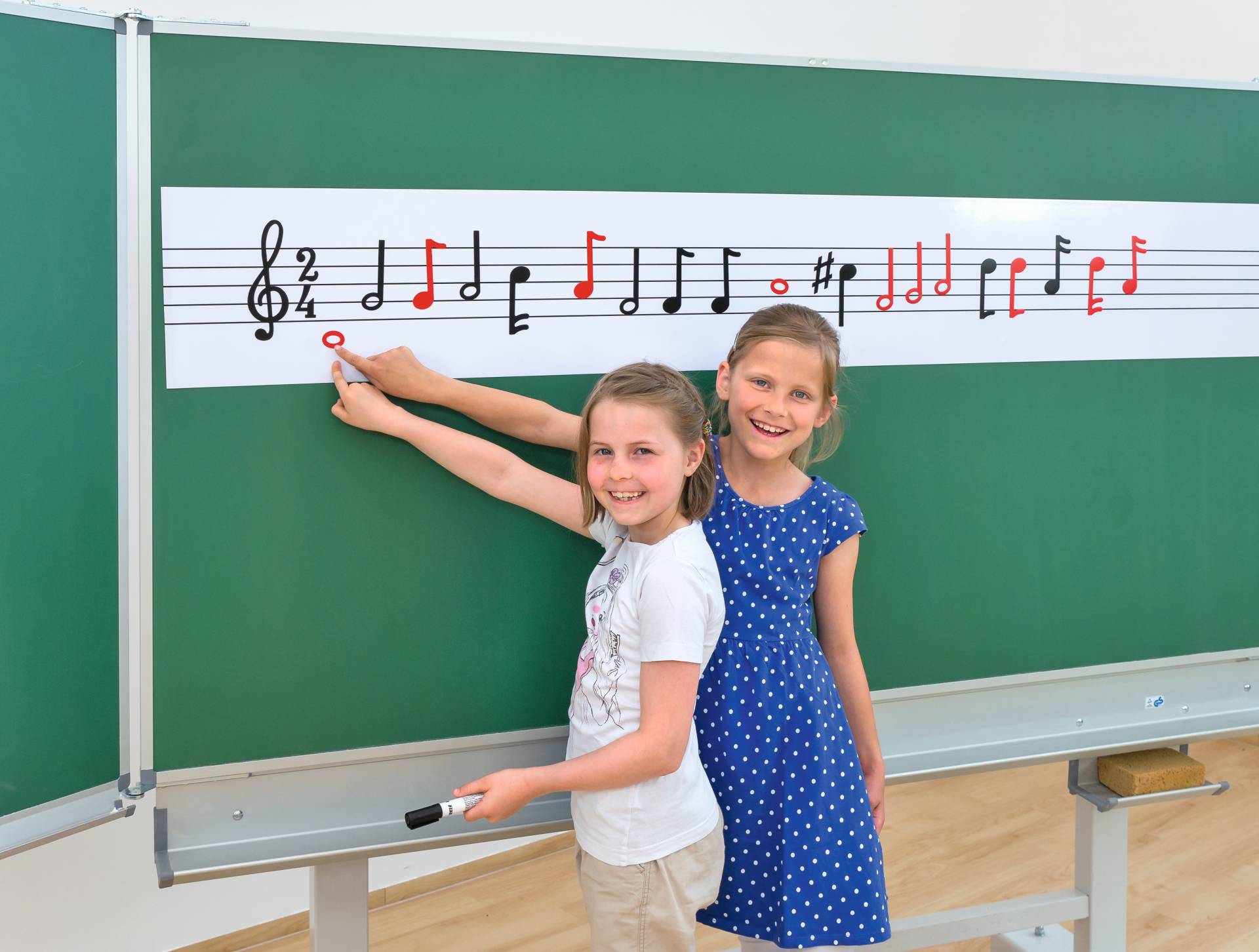 Twee kinderen plaatsen magnetische noten op een notenbalk op een schoolbord, leren muzieknotatie.