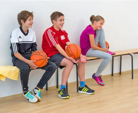 Stapelbare garderobebank van 160 cm in beukenhout, zwart/grijs, met drie kinderen die basketballen vasthouden.