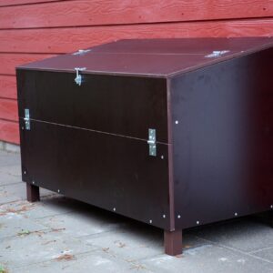 Robuuste, weerbestendige Outdoor Multibox voor buitenopslag, geplaatst tegen een rode wand, met scharnierende deksel.