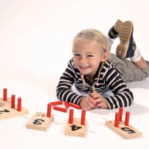 Houten pinplankjes met cijfers en rode pinnen, gebruikt door een lachend kind voor het leren tellen en patronen maken.
