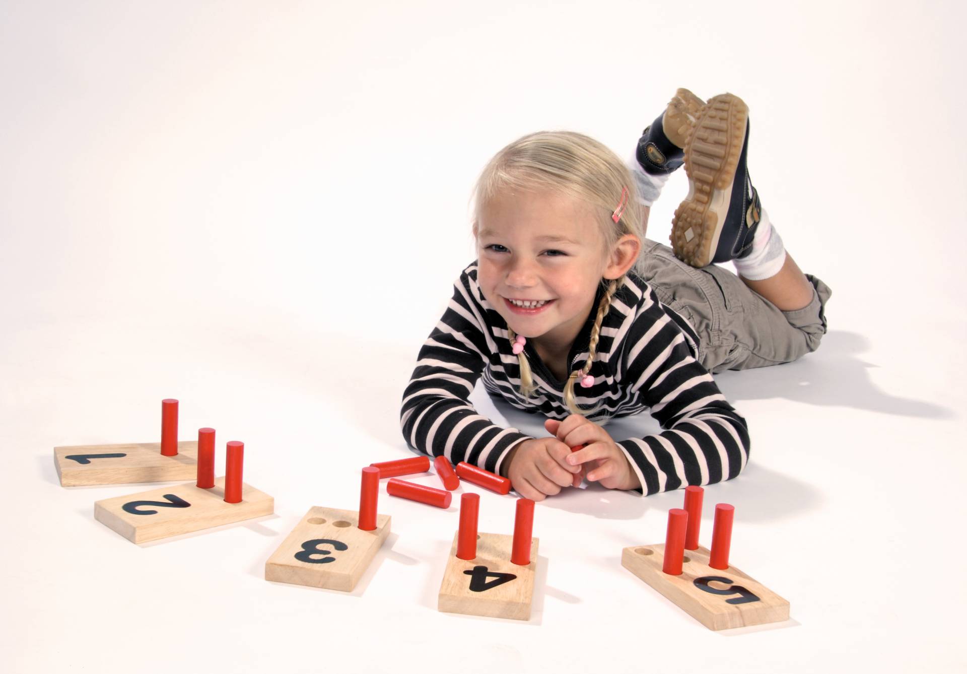 Houten pinplankjes met cijfers en rode pinnen, gebruikt door een lachend kind voor het leren tellen en patronen maken.