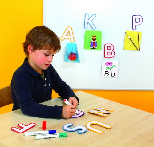 Kleurrijke plastic letters van 11,5 cm, set van 26, gebruikt door een jongen voor schrijfactiviteiten op een tafel.