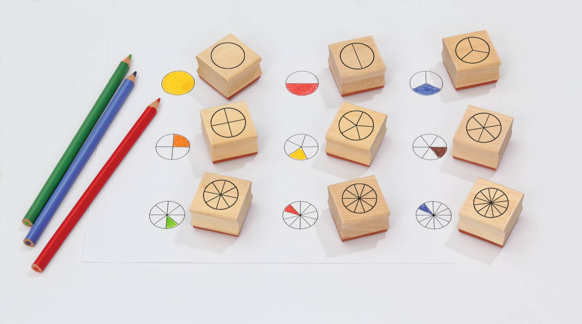 Breuken stempels (9 st.) op een blad papier met gekleurde stiften, ideaal voor leren rekenen met breuken.