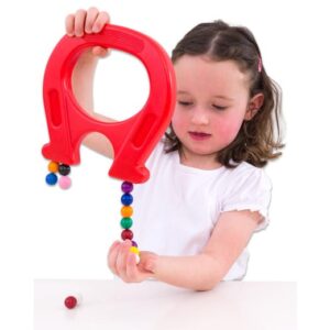 Magneetkogels ∅ 15mm in diverse kleuren, met een kind dat ze vasthoudt en speelt met een grote rode magneet.