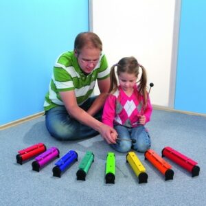 Kleurige Rainbow Sound tubes in een rechte lijn, met een man en een meisje die samen muziek maken op de vloer.