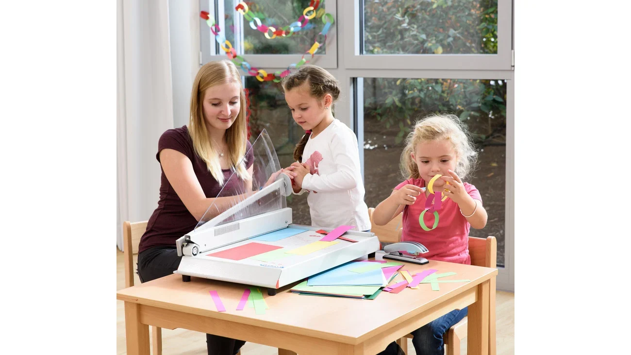 Snijmachine Betzold A3 in gebruik door drie kinderen aan een tafel, met kleurrijk papier en knutselmaterialen.