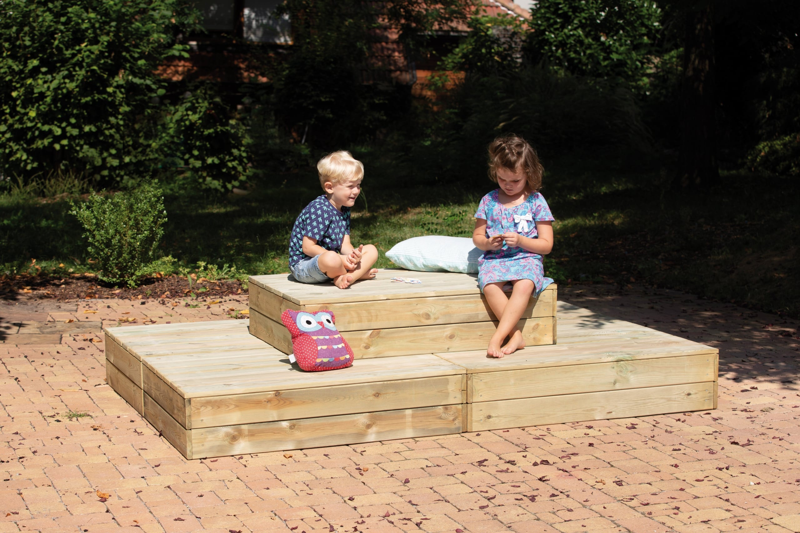 Comfortabel Lounge Podium met verschillende niveaus, waar kinderen ontspannen en spelen, omringd door groen.