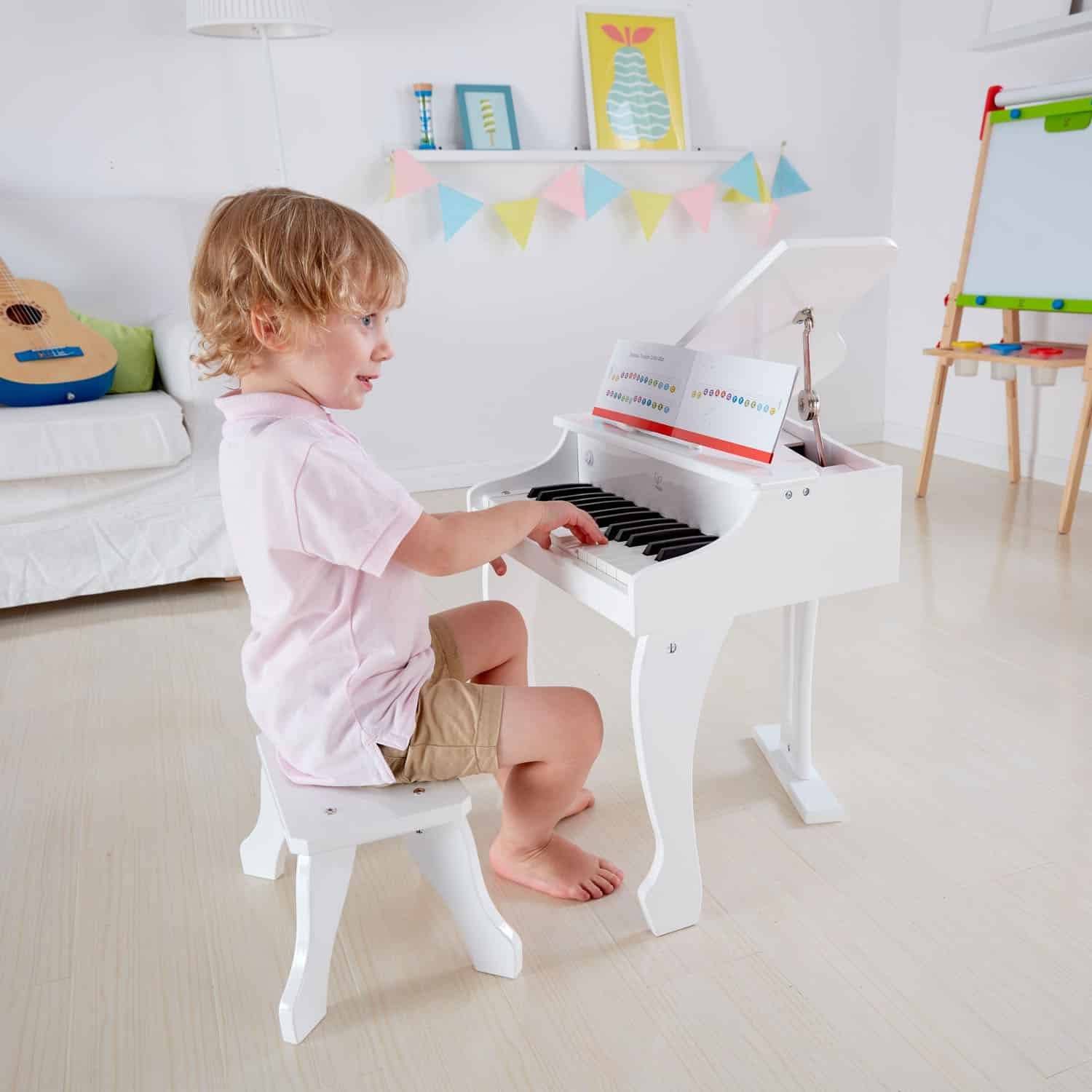 Kind speelt op de Hape Piano XL, een wit houten speelgoedpiano met kindvriendelijke toetsen en bladmuziek.