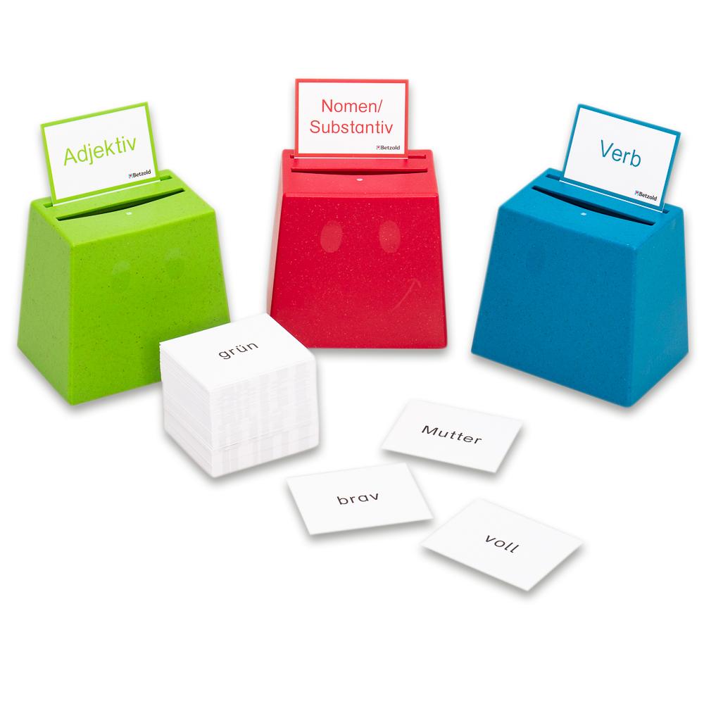 Drie kleurrijke doosjes voor het spel Cup Quizzer, met kaarten voor adjectieven, zelfstandige naamwoorden en werkwoorden.