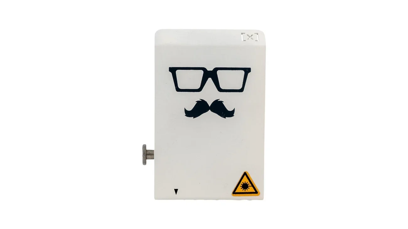 Mr Beam II dreamcut Laserkop met een witte behuizing, bril en snor als decoratie, en waarschuwingssymbool voor laser.