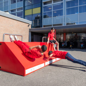 Kinderen in rode kleding gebruiken de Fitstation Schoolplein Fitness, een feloranje fitnessmeubel voor buiten.