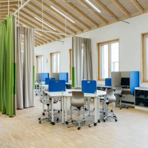 Groene en blauwe concentratieschermen in een moderne klaslokaalsetting, met flexibele tafels en stoelen.