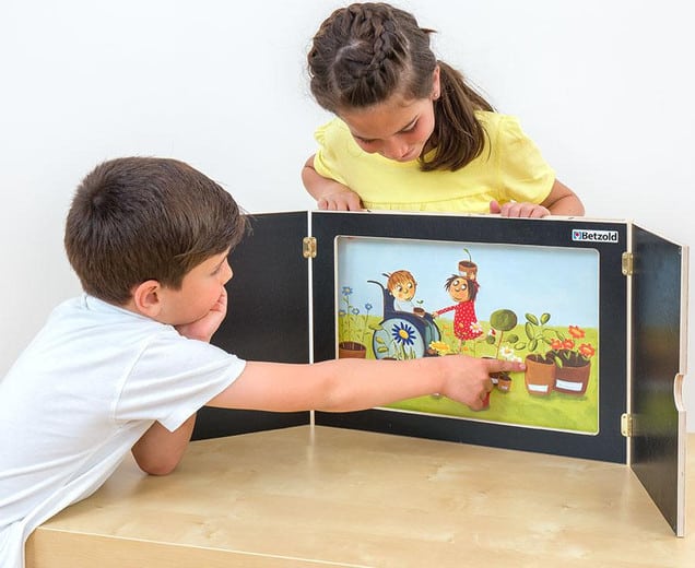 Kamishibai verteltheater met kinderen die naar een kleurrijk verhaal kijken en wijzen naar de afbeeldingen.