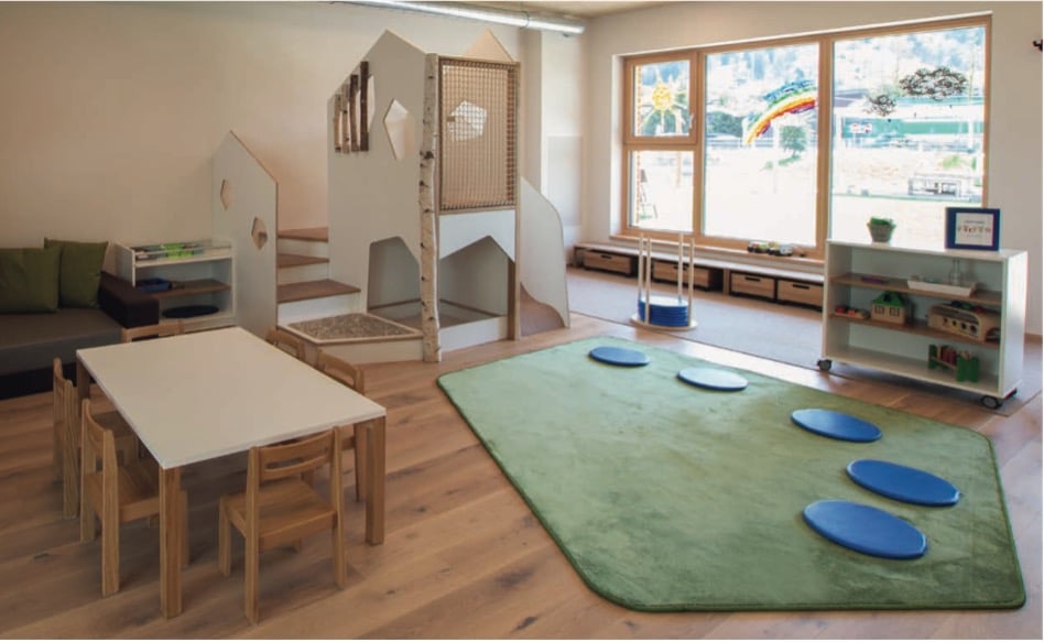 Groen vloerkleed op maat in een speelhoek met houten meubels en een speelstructuur voor kinderen.