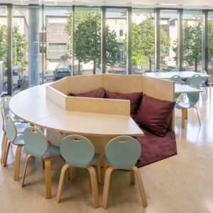 Cirkelvormige opstelling met houten tafels en stoelen, biedt een warme, vertrouwde omgeving voor kinderen.