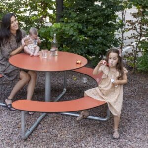 Ronde picknickbank met metalen onderstel, kinderen en volwassene genieten van een maaltijd in een groene omgeving.